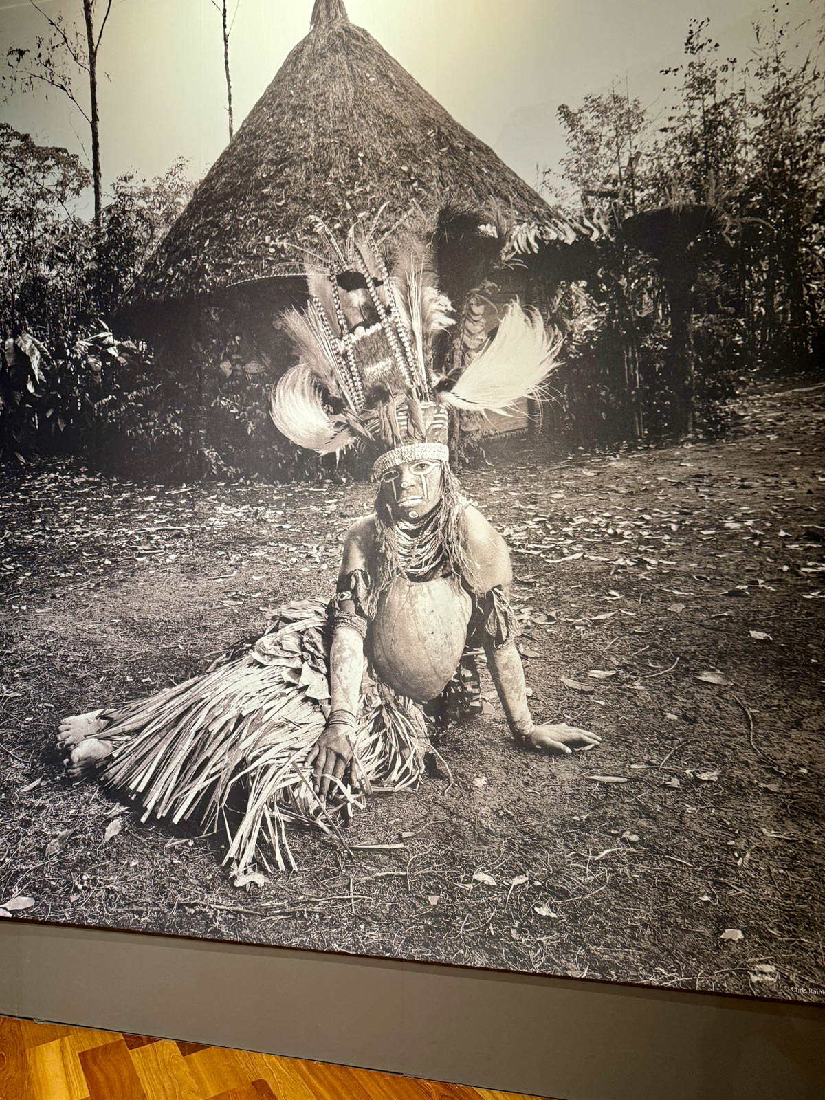 Black and white photograph of young woman in tribal dress at museum.
