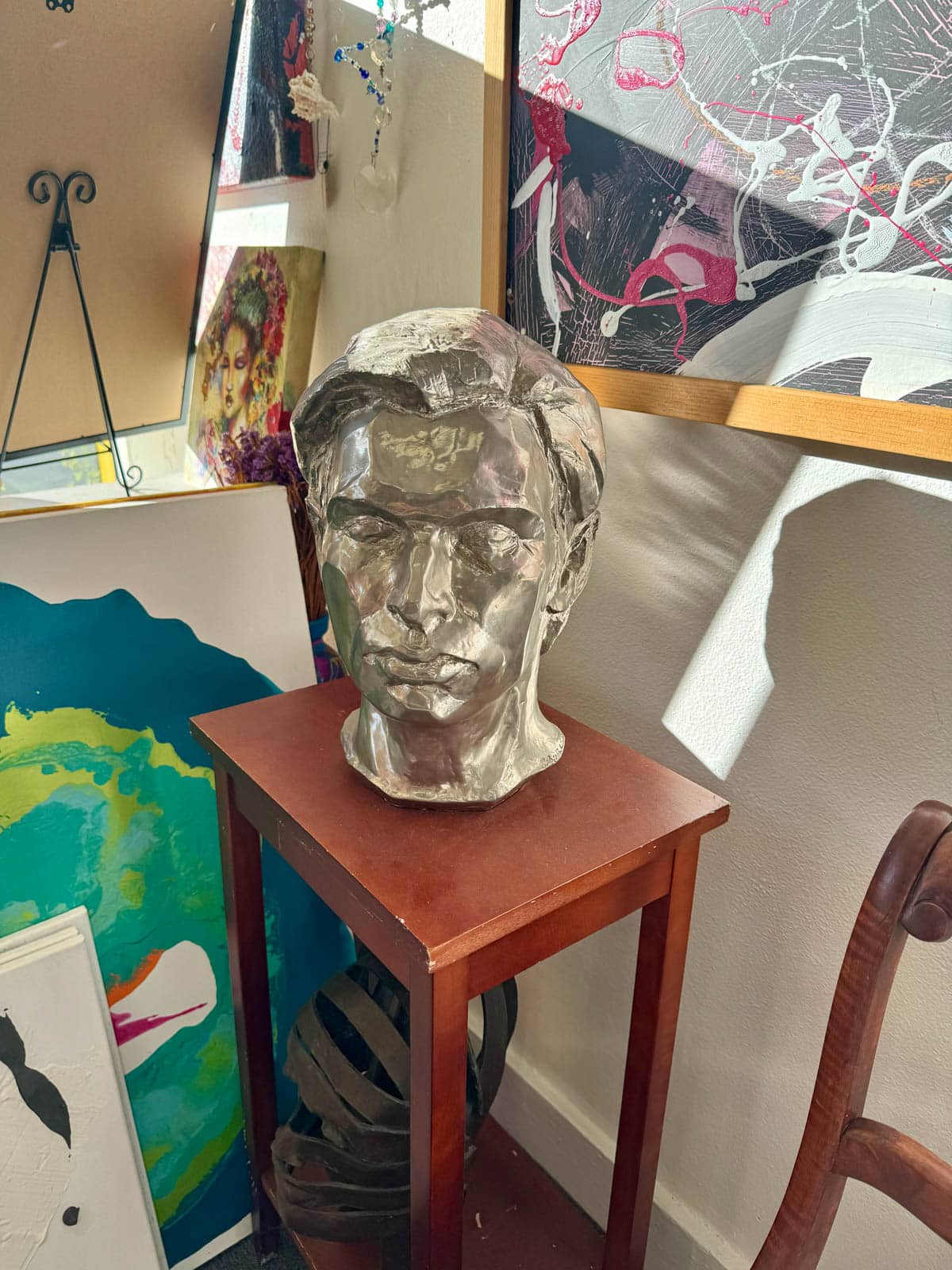 Photo of sculpture of a man's head on a wooden table in a gallery.