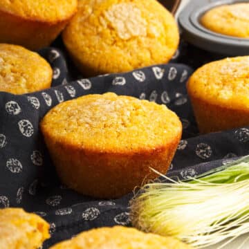 Corn bread muffins in corn husks and black napkin.
