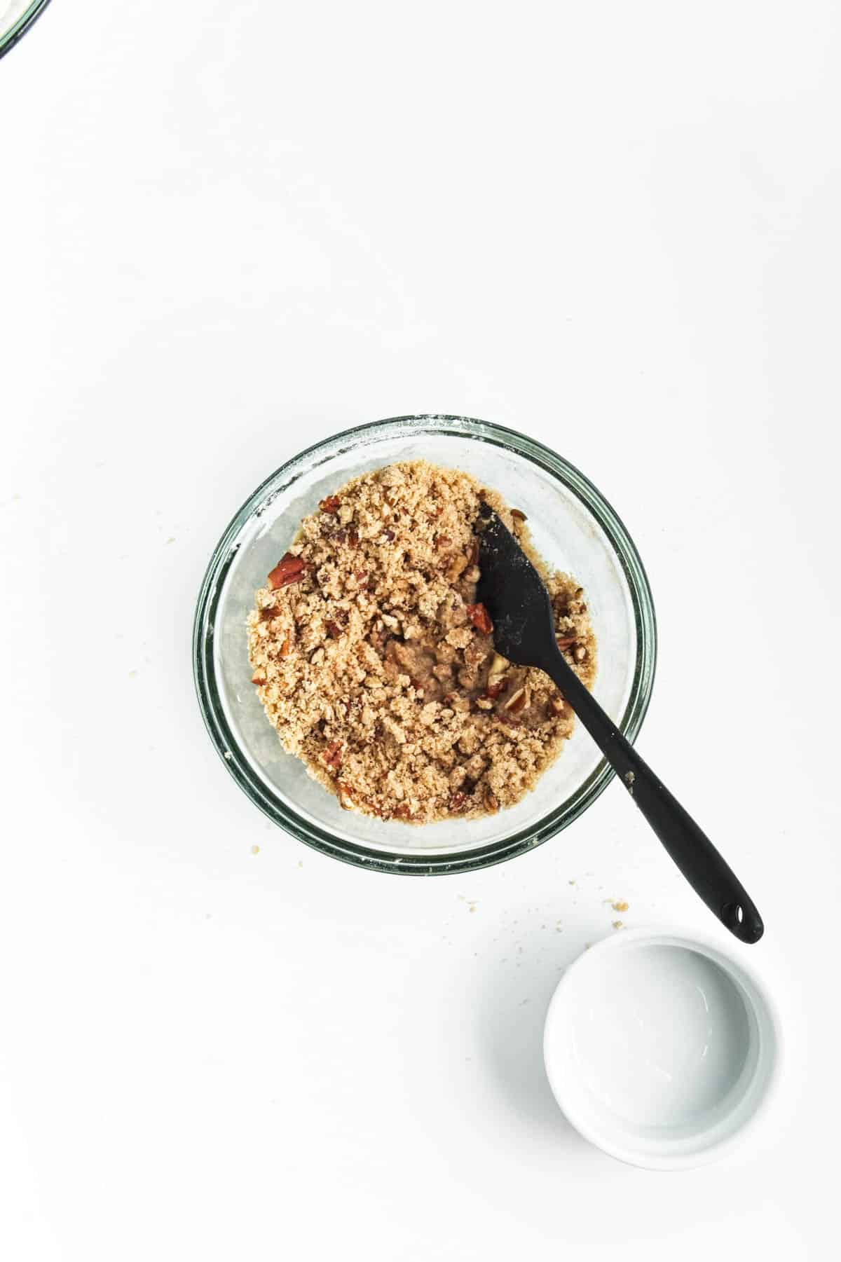 Streusel in a glass bowl with a black spatula.