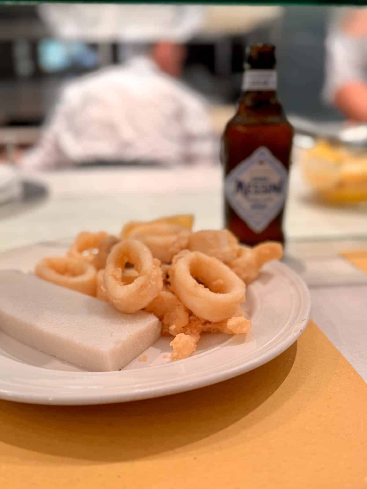 Fried calamari with a bottle of beer in background.