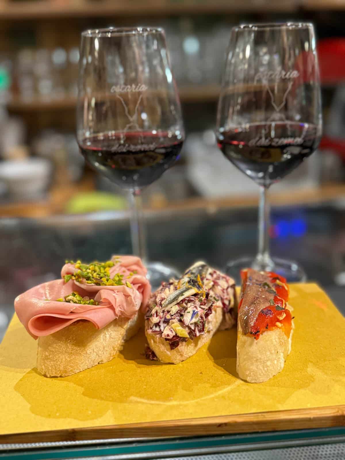 Appetizers on baguettes with glasses of wine.