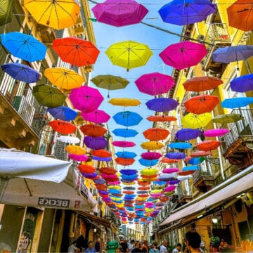 Catania market with colorful umbrellas overhead.