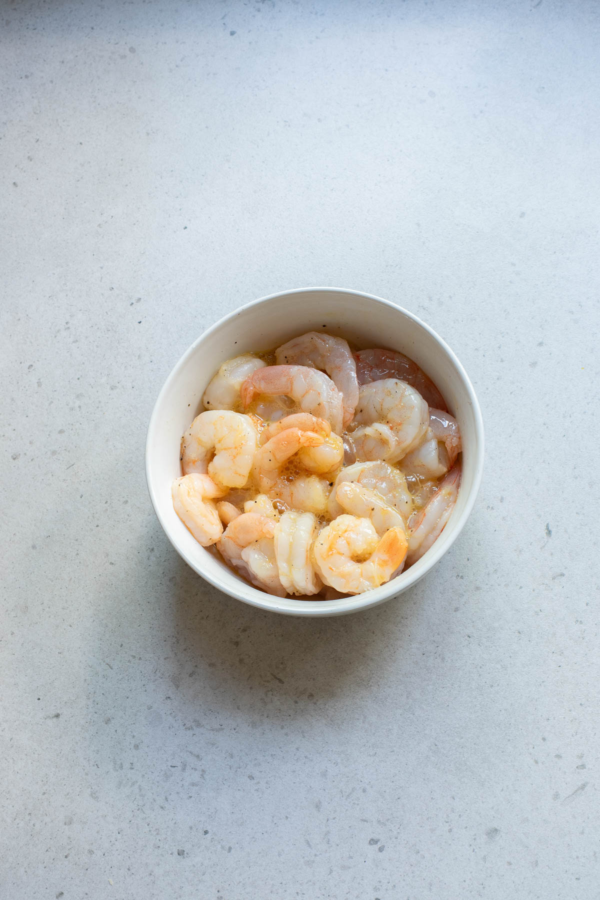 raw shrimp in a white bowl on counter.