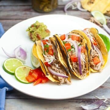 Meat tacos on a white plate.