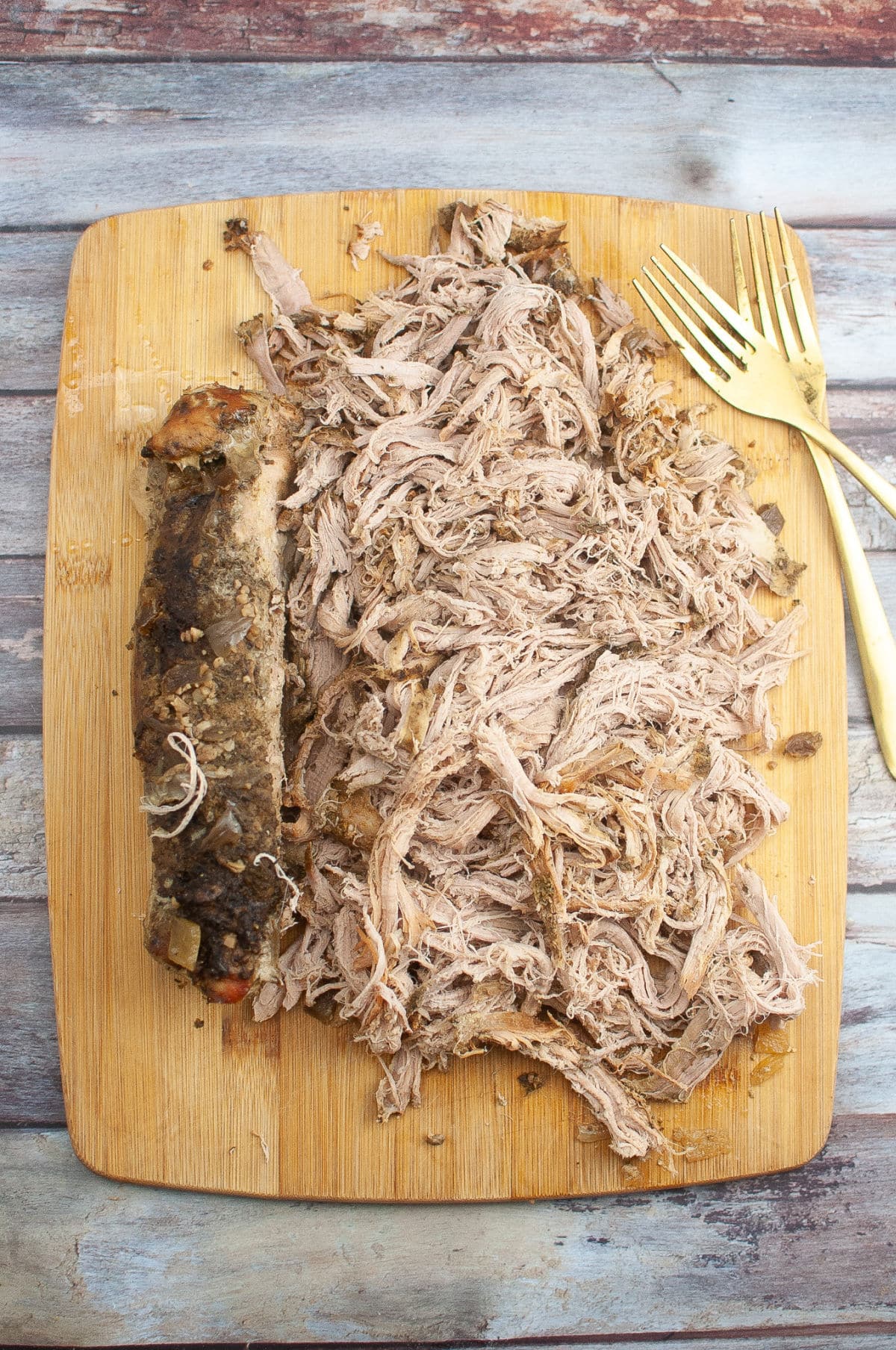 Shredded meat on cutting board with two forks.