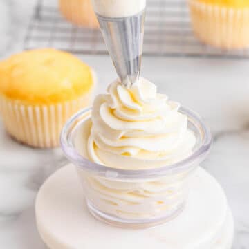Whipped cream being piped into a glass bowl.