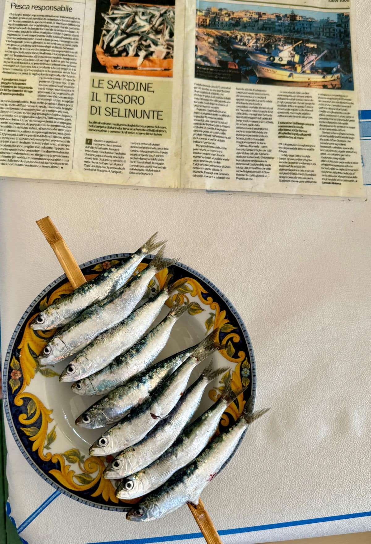Sardines on skewer with newspaper article above.