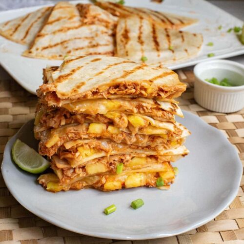 Quesadillas with cheese and chicken stacked on a plate.