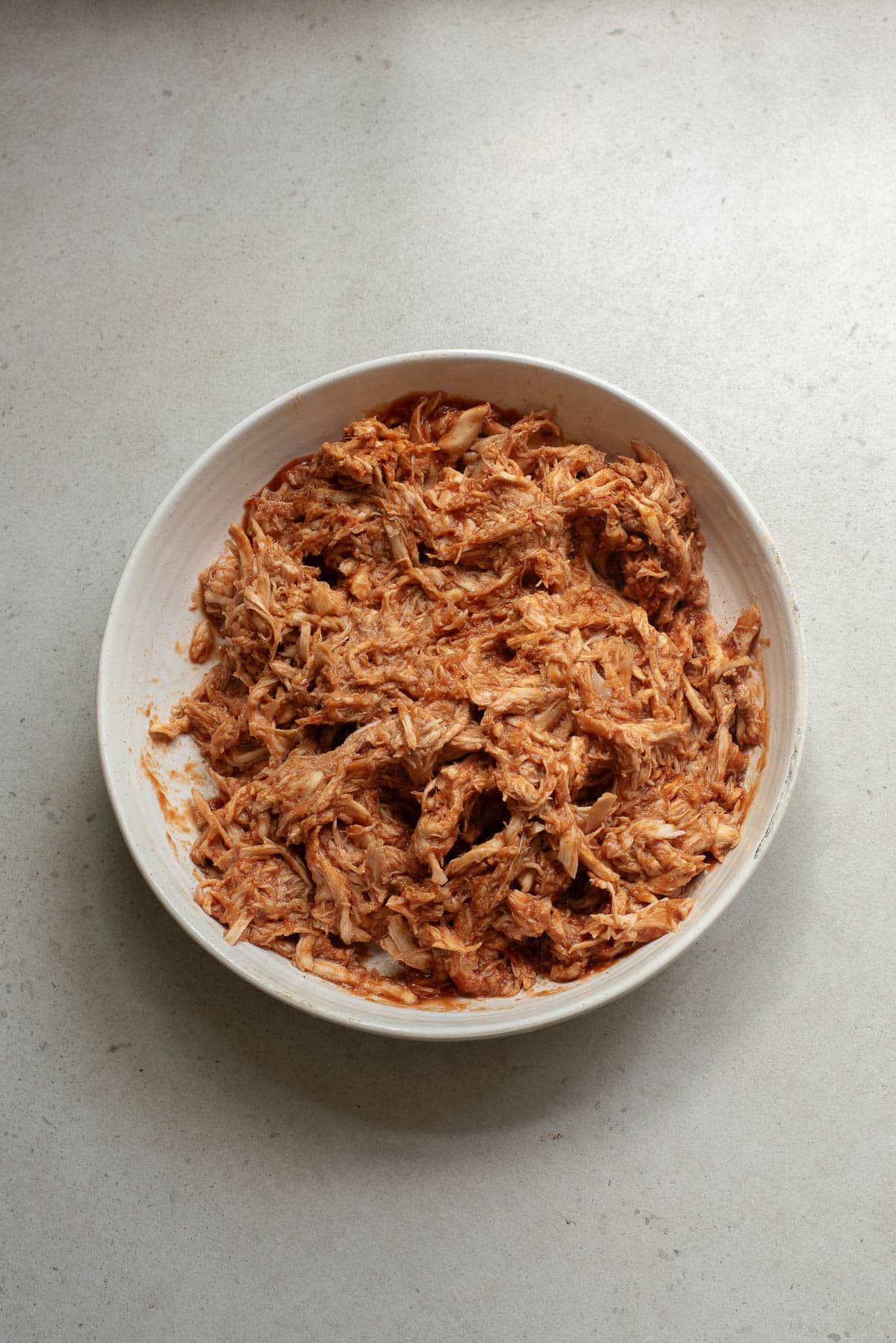 Shredded barbecue chicken in a white bowl.