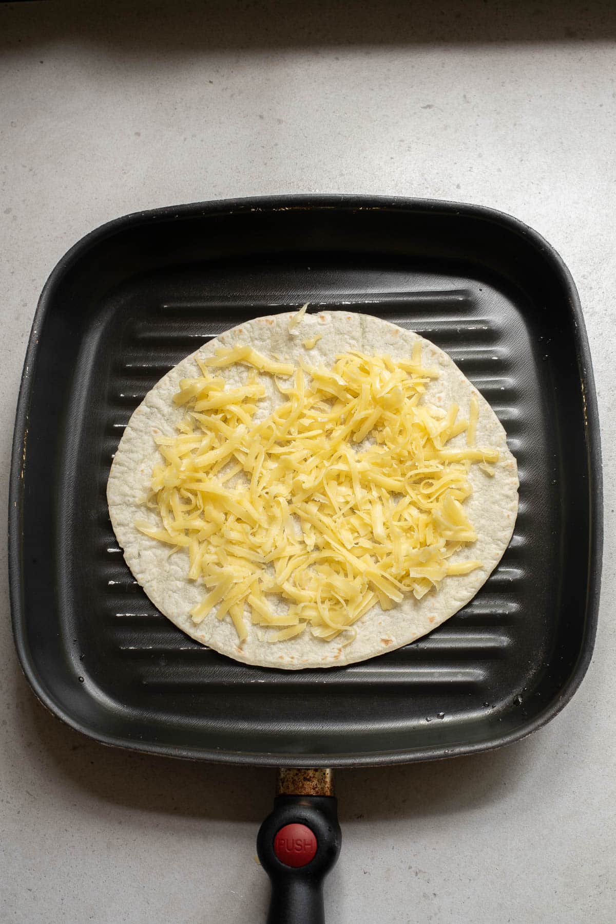 Tortilla with cheese on a griddle.