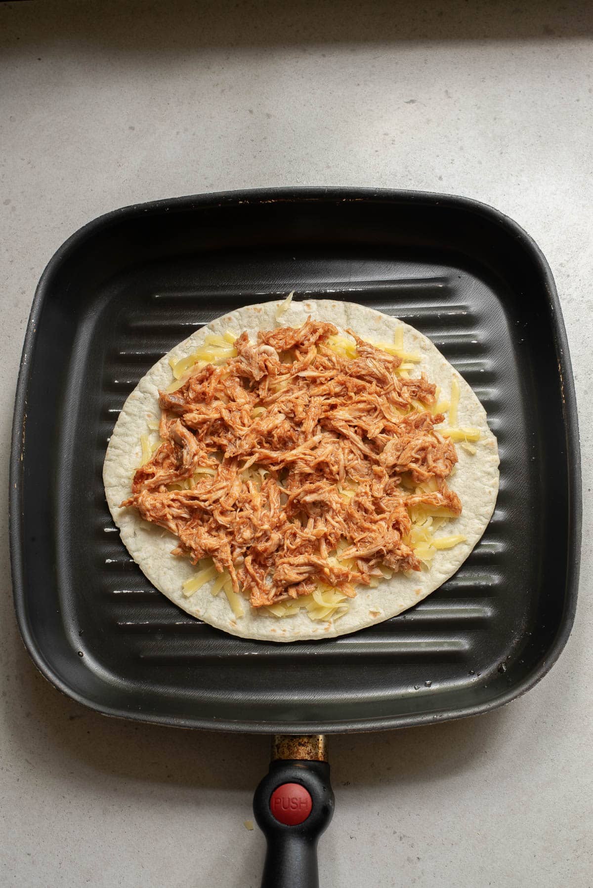 Tortilla with chicken and cheese on a griddle.