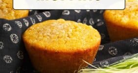 Cornbread muffins on a black napkin with ear of corn in front.