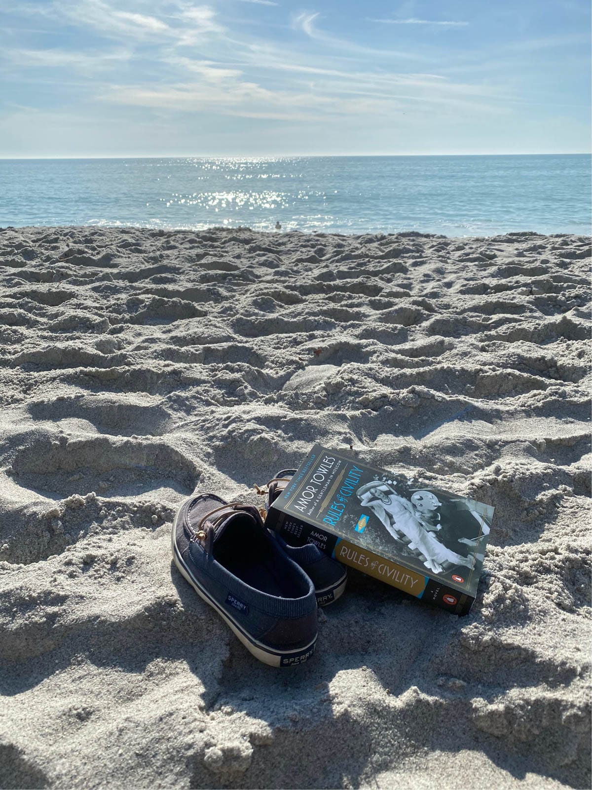 Book and shoes in the sand at the beach.