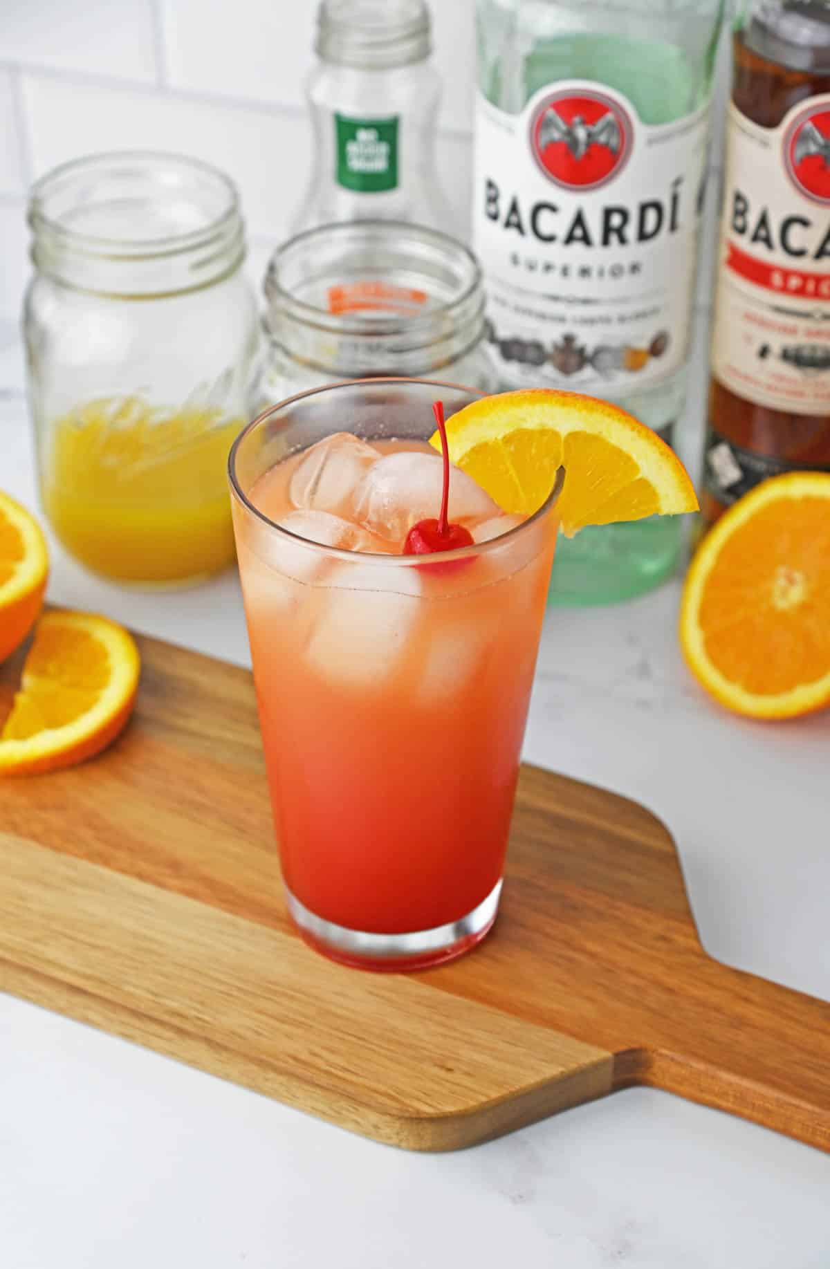 A tropical drink served in a tall glass with cherries and orange slices.
