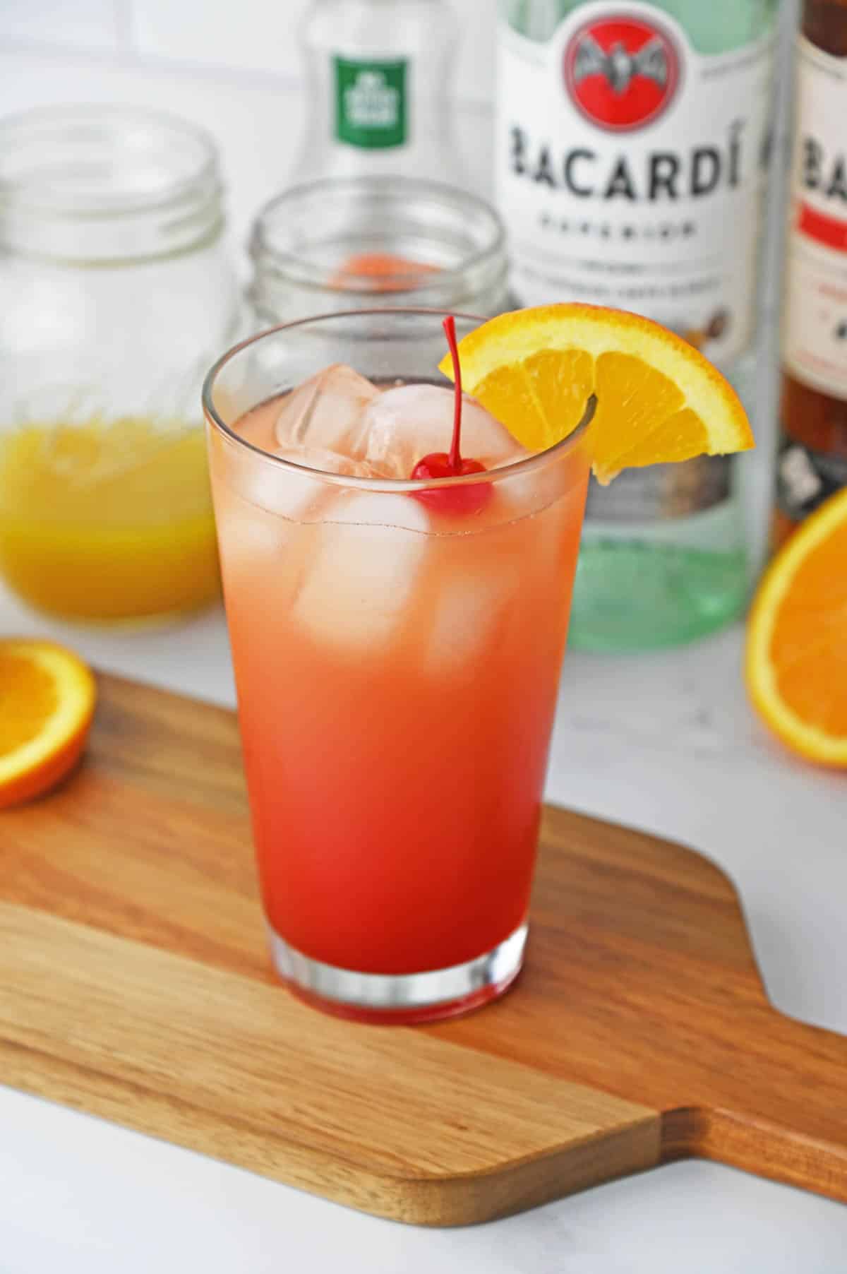 A tropical drink served in a tall glass with cherries and orange slices.