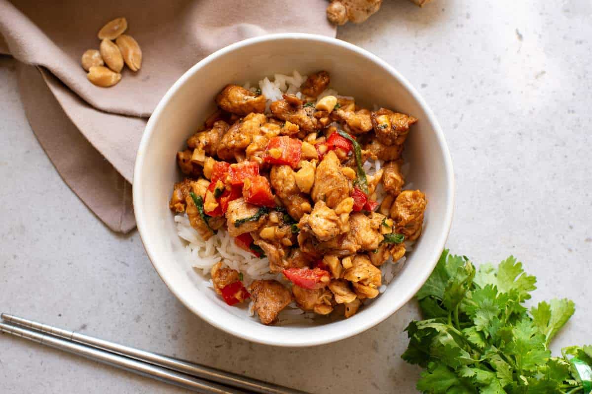 Chicken stir fry in a white bowl with chopsticks.