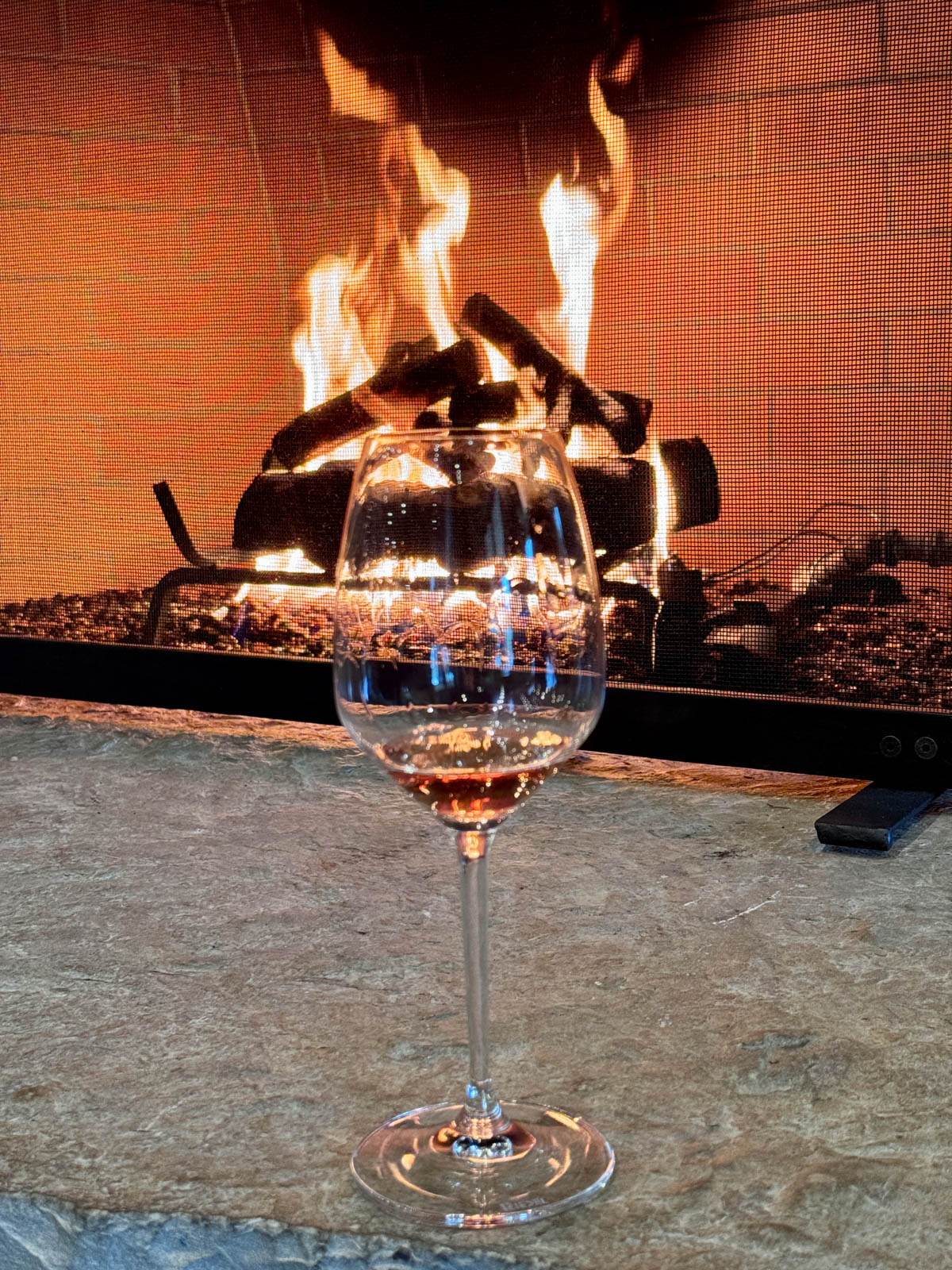 Glass of wine in front of a fireplace.