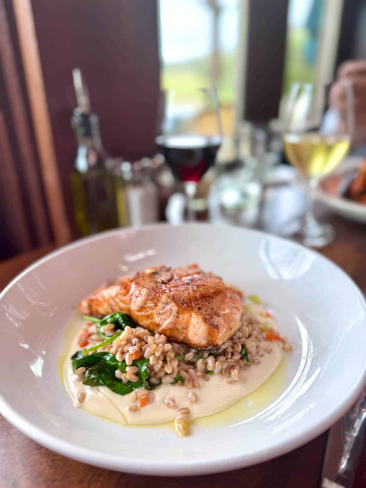 Salmon on top of grains and spinach with sauce.