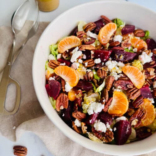 Toss with beets, lettuce, orange slices, feta cheese, pecans and balsamic dressing in a white bowl.
