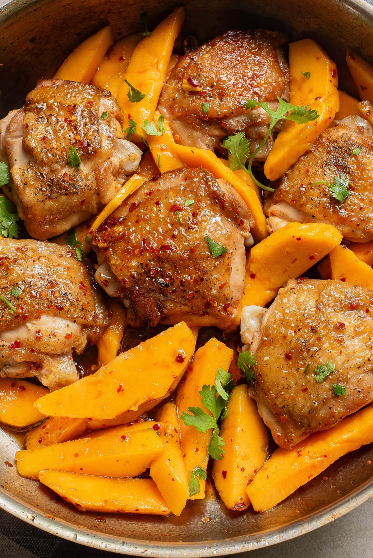 Chicken and mango slices in a pan.