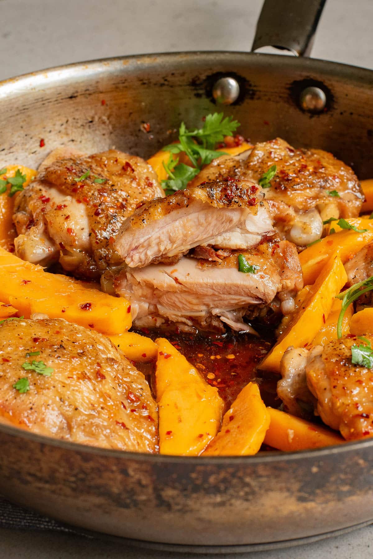 Chicken and mango slices in a pan with sauce.