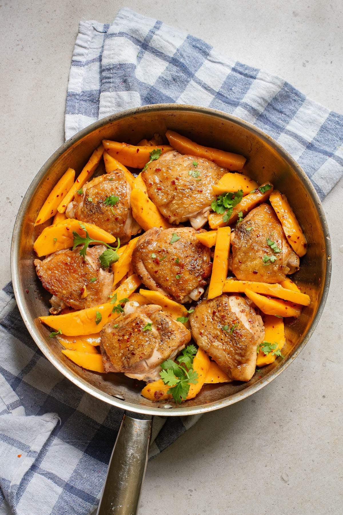 Chicken and mango slices in a pan with cilantro.