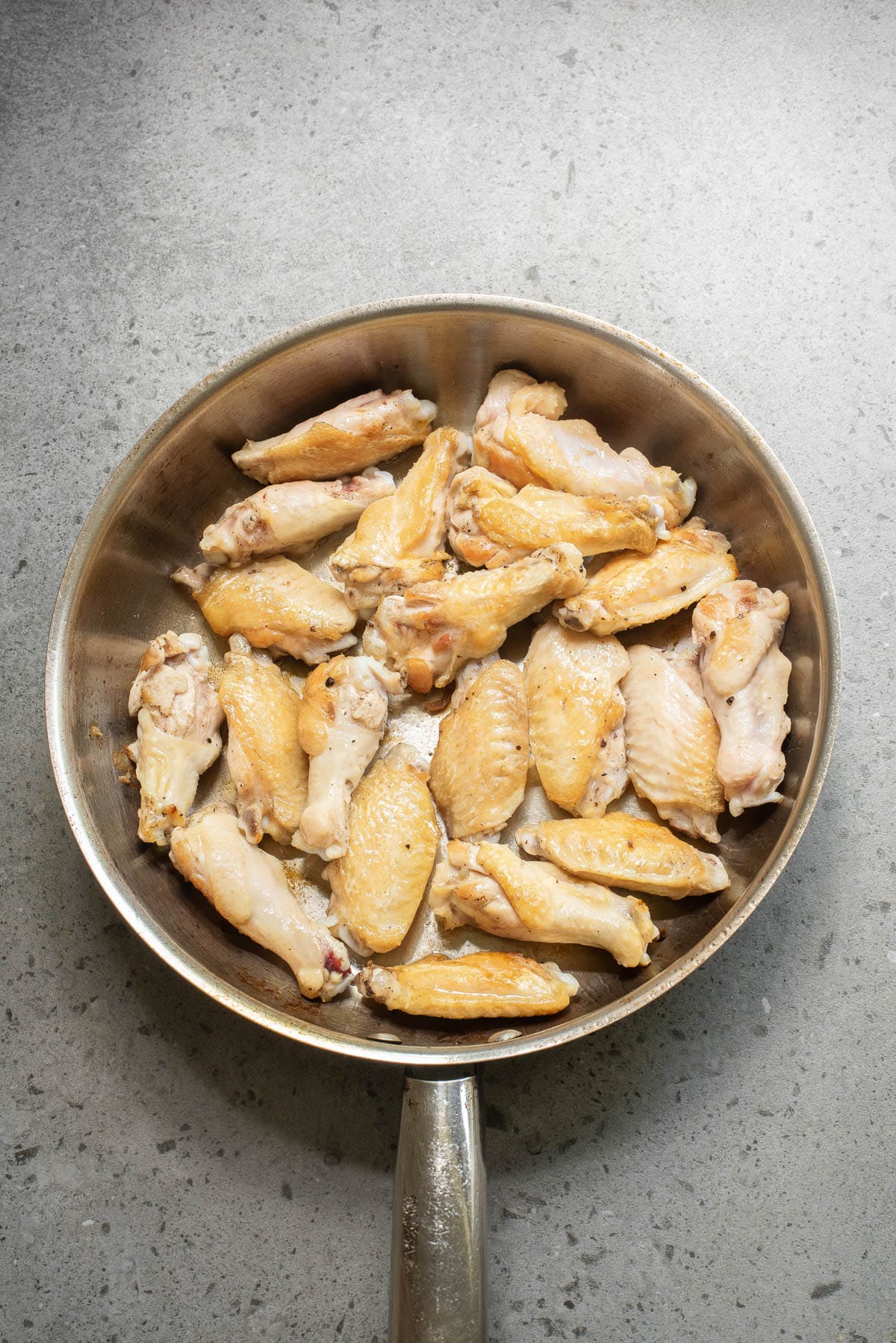 Chicken wings in a skillet.