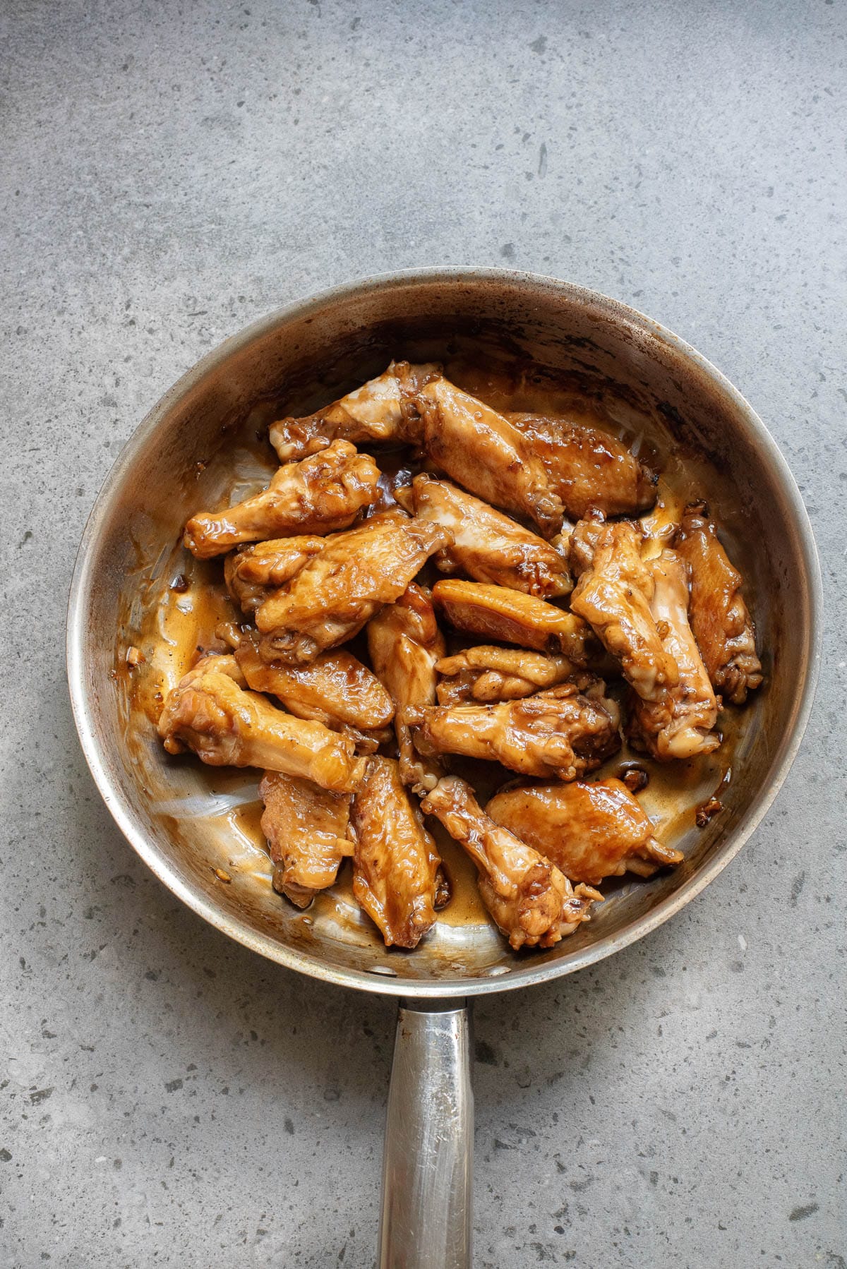 Chicken wings and sauce in a skillet.