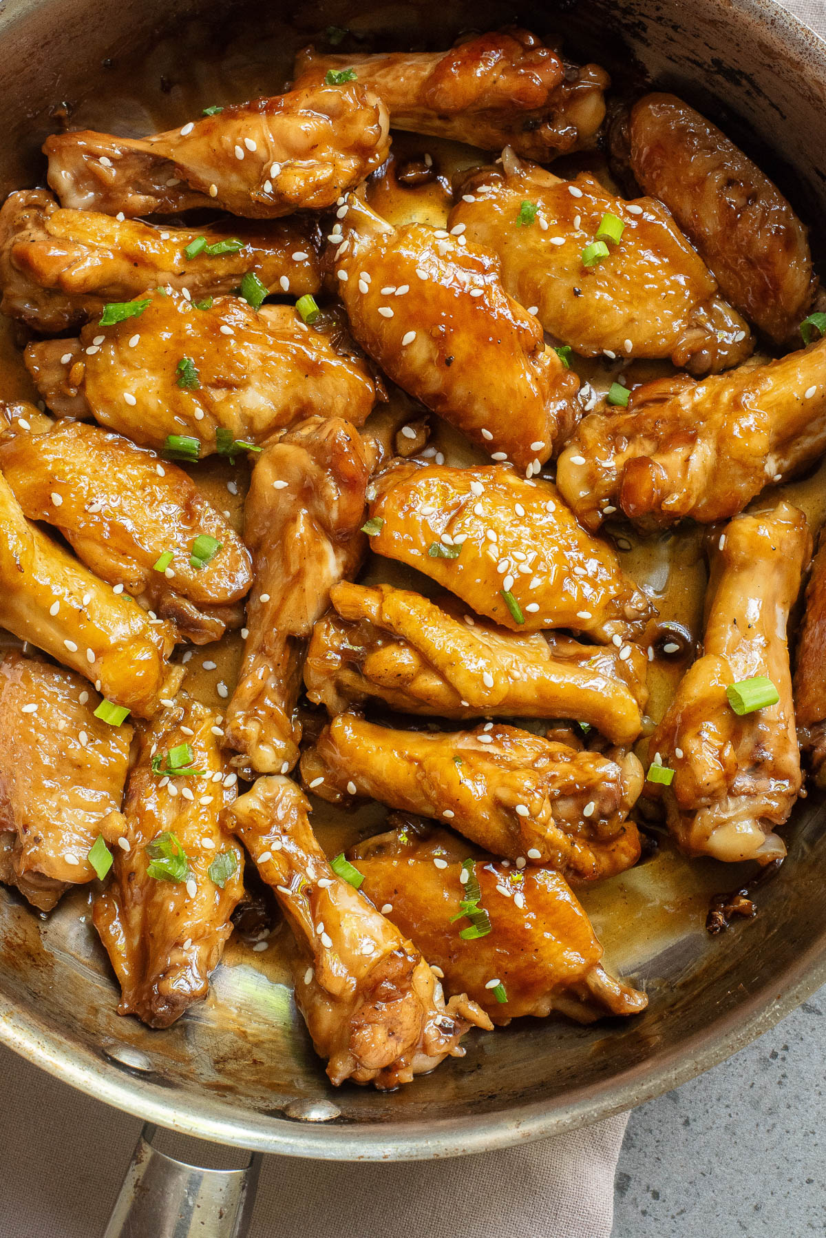 Chicken wings in sauce in a skillet.
