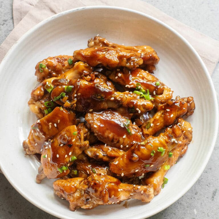 Chicken wings with a sweet sauce topped with sesame seeds and green onion.