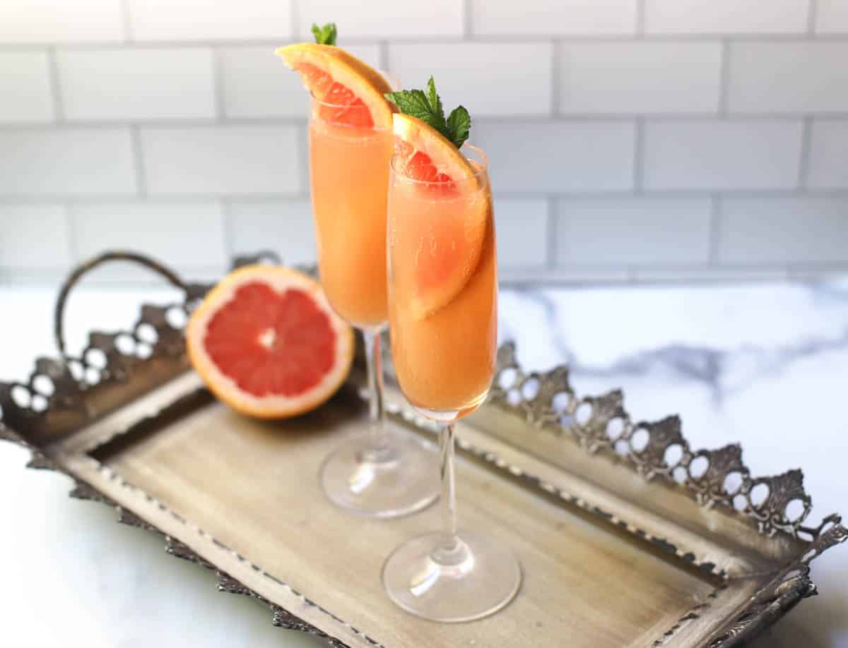 Grapefruit mimosa in a flute glass on a tray.