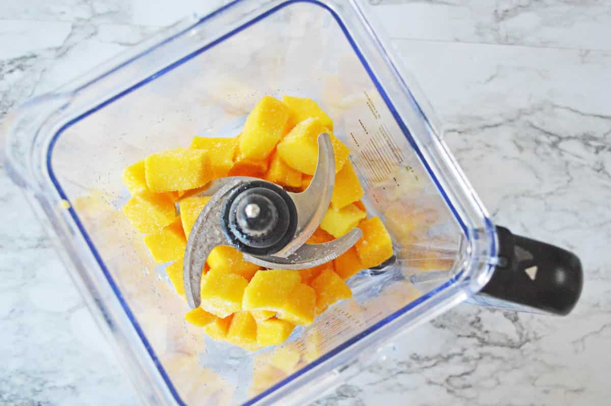 Frozen mango chunks in a blender.