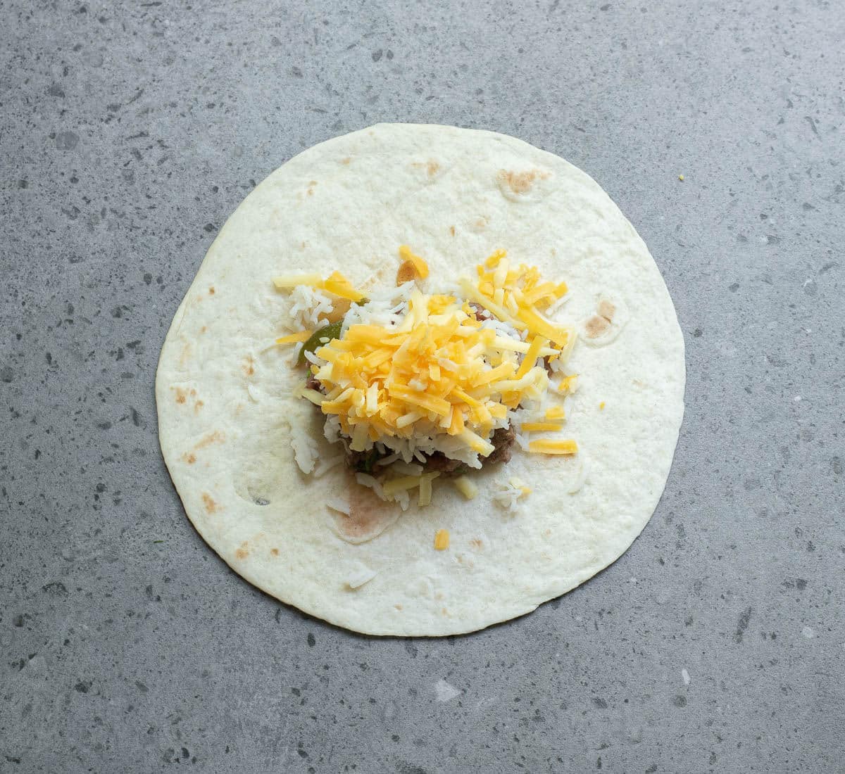 Tortillas with beef, beans and cheese on a gray counter.