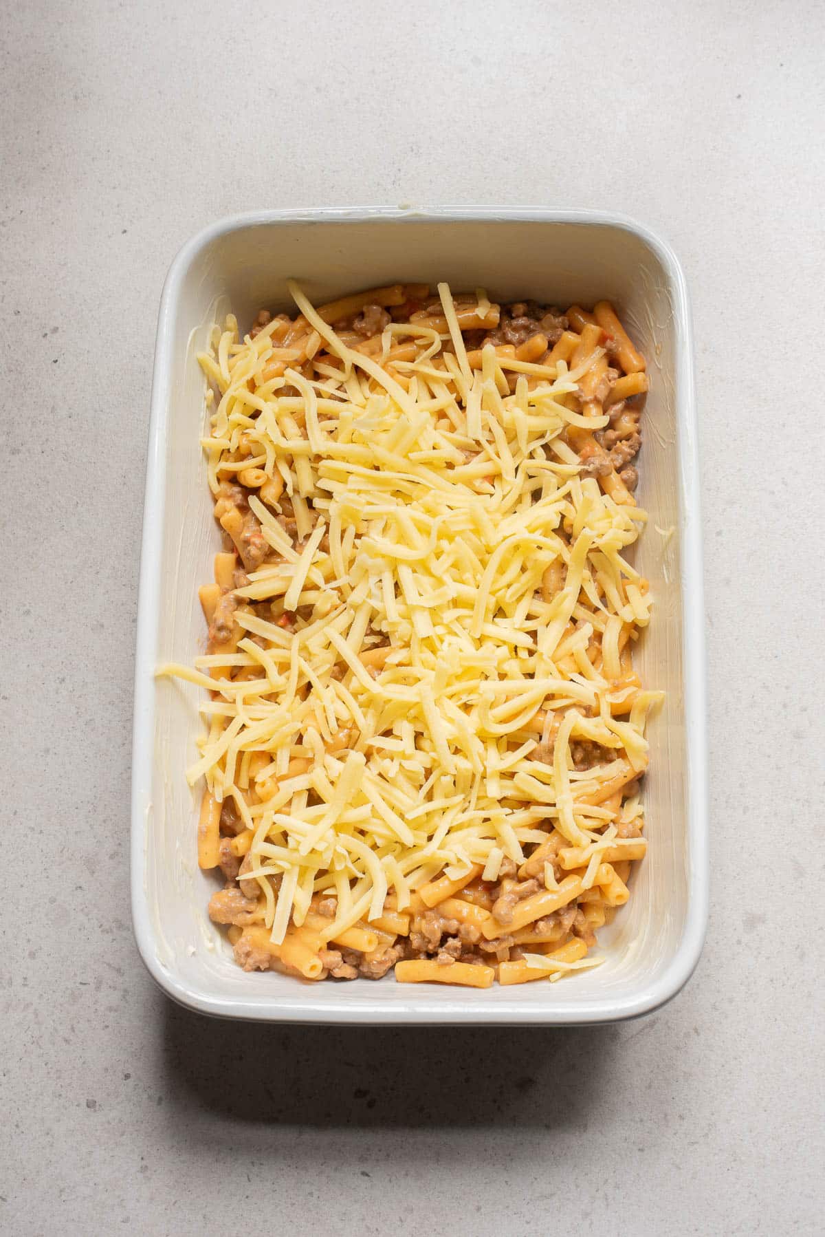 Pasta mixture topped with cheese in a casserole dish.