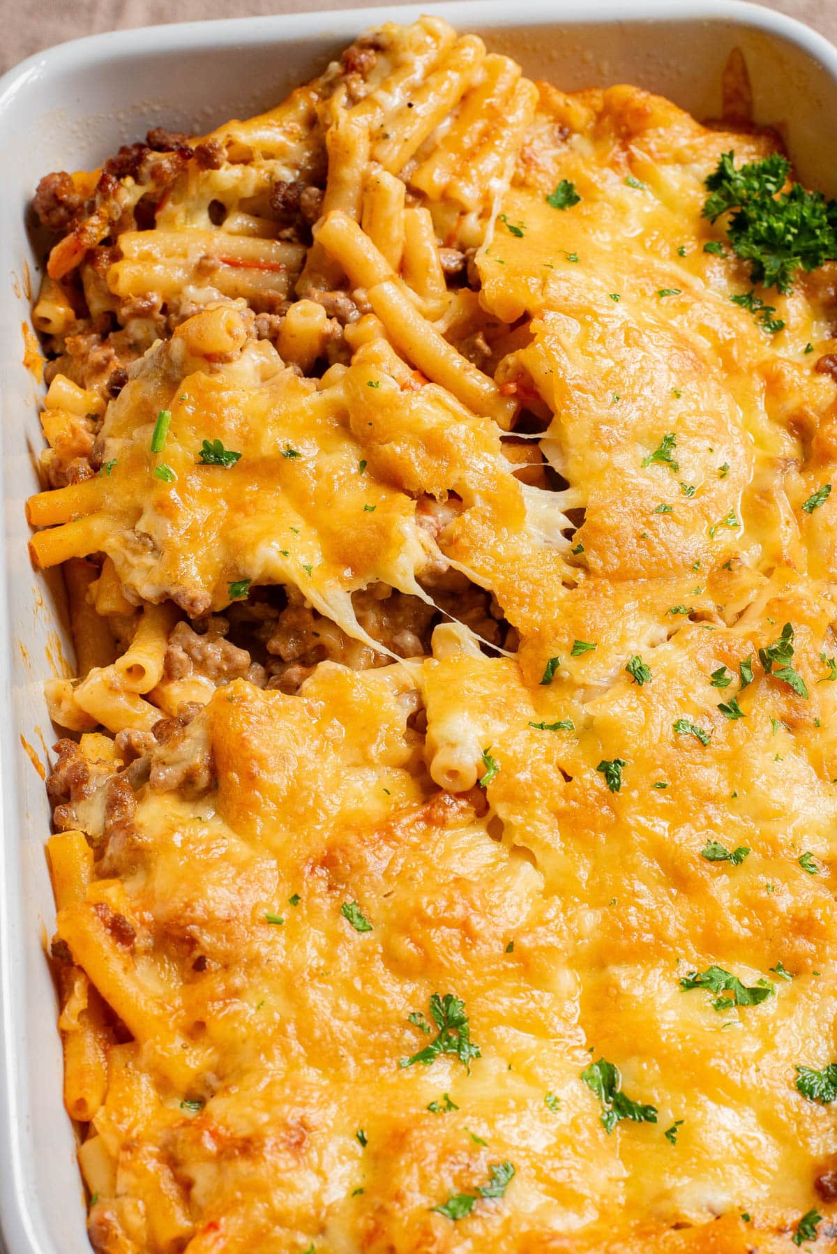 Baked ziti topped with cheese in a casserole dish.