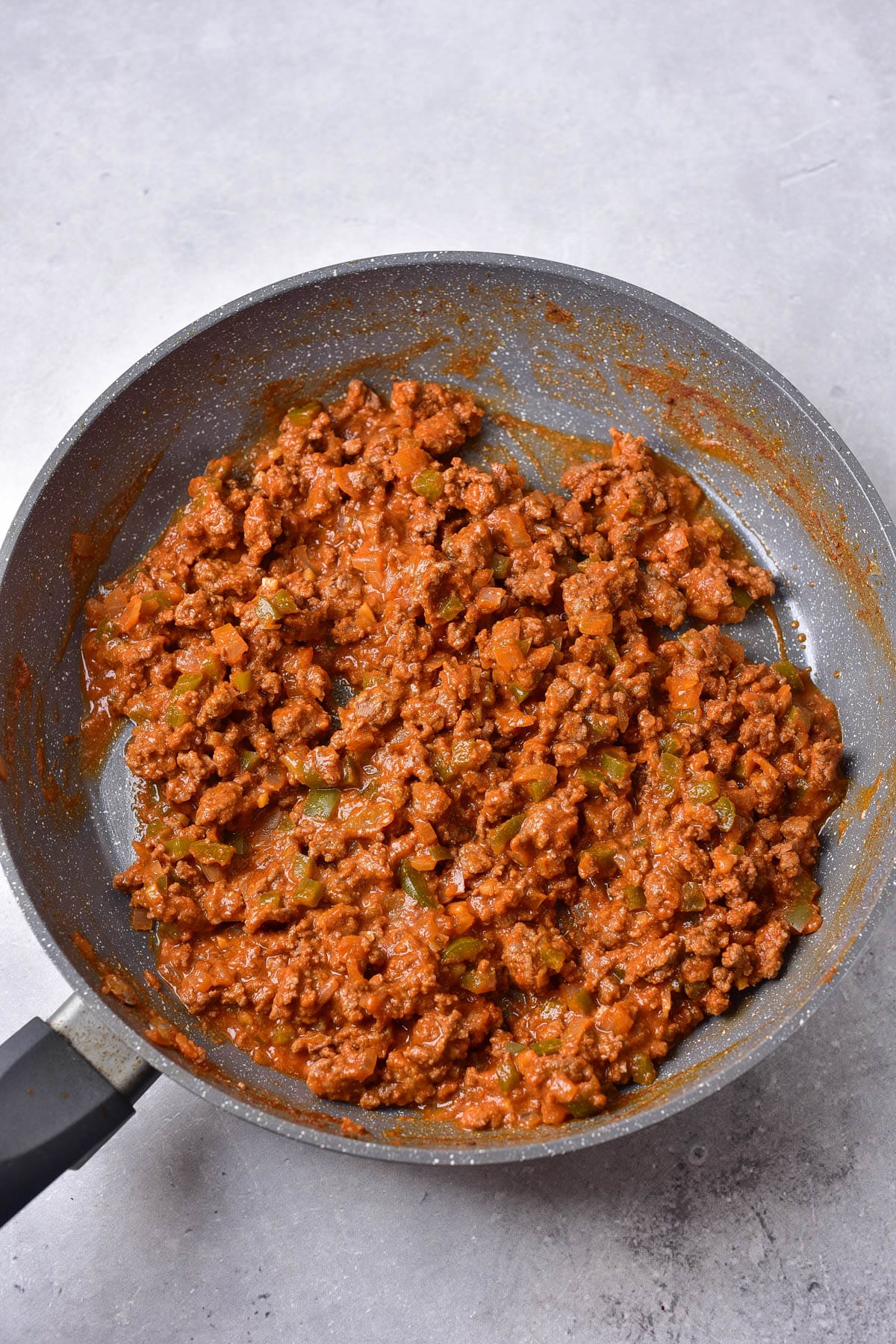 Ground beef with tomato based sauce in skillet.