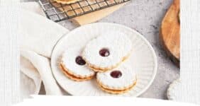 Cookies with jam and powdered sugar on a white plate on napkin with more cookies in background graphic for Pinterest.