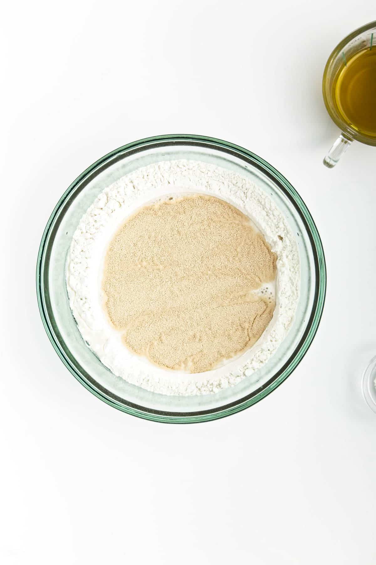Flour, water, and yeast in a glass bowl.