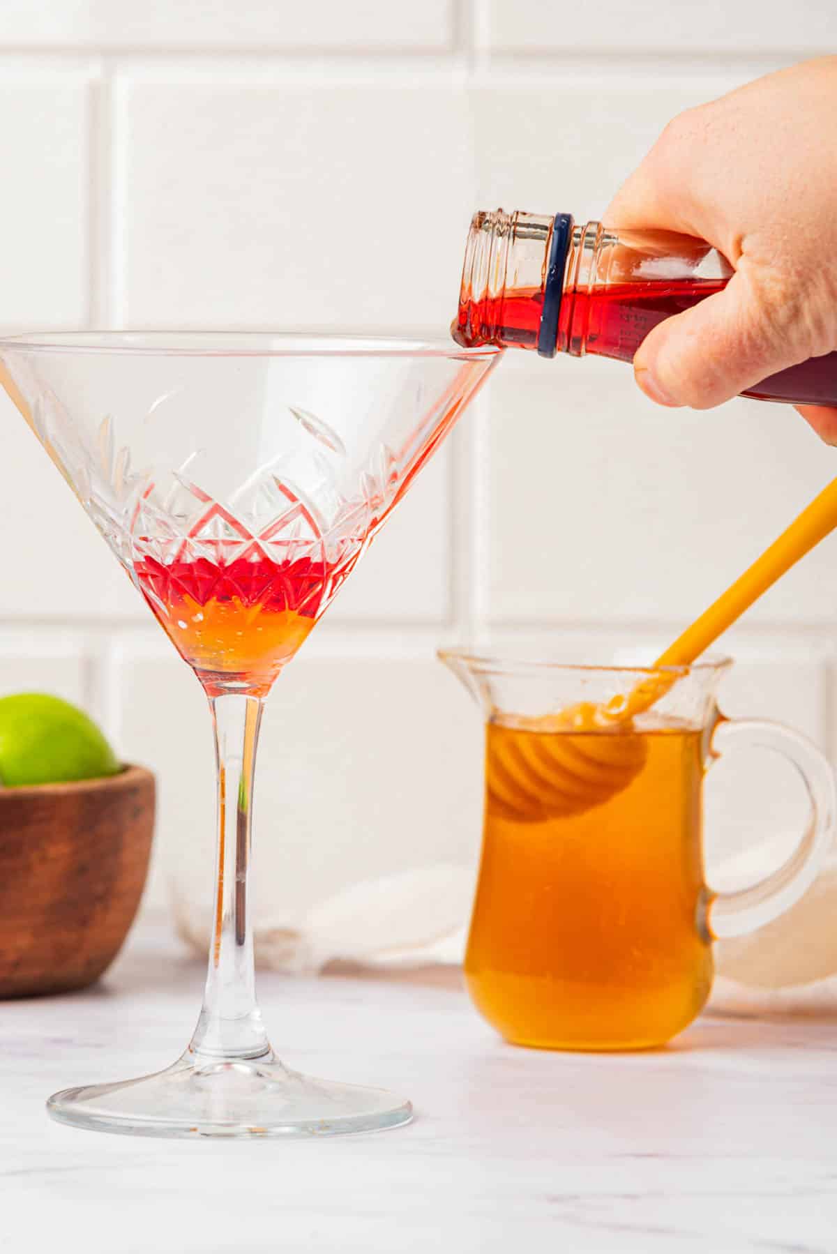 Pouring red liquid over honey in a martini glass.