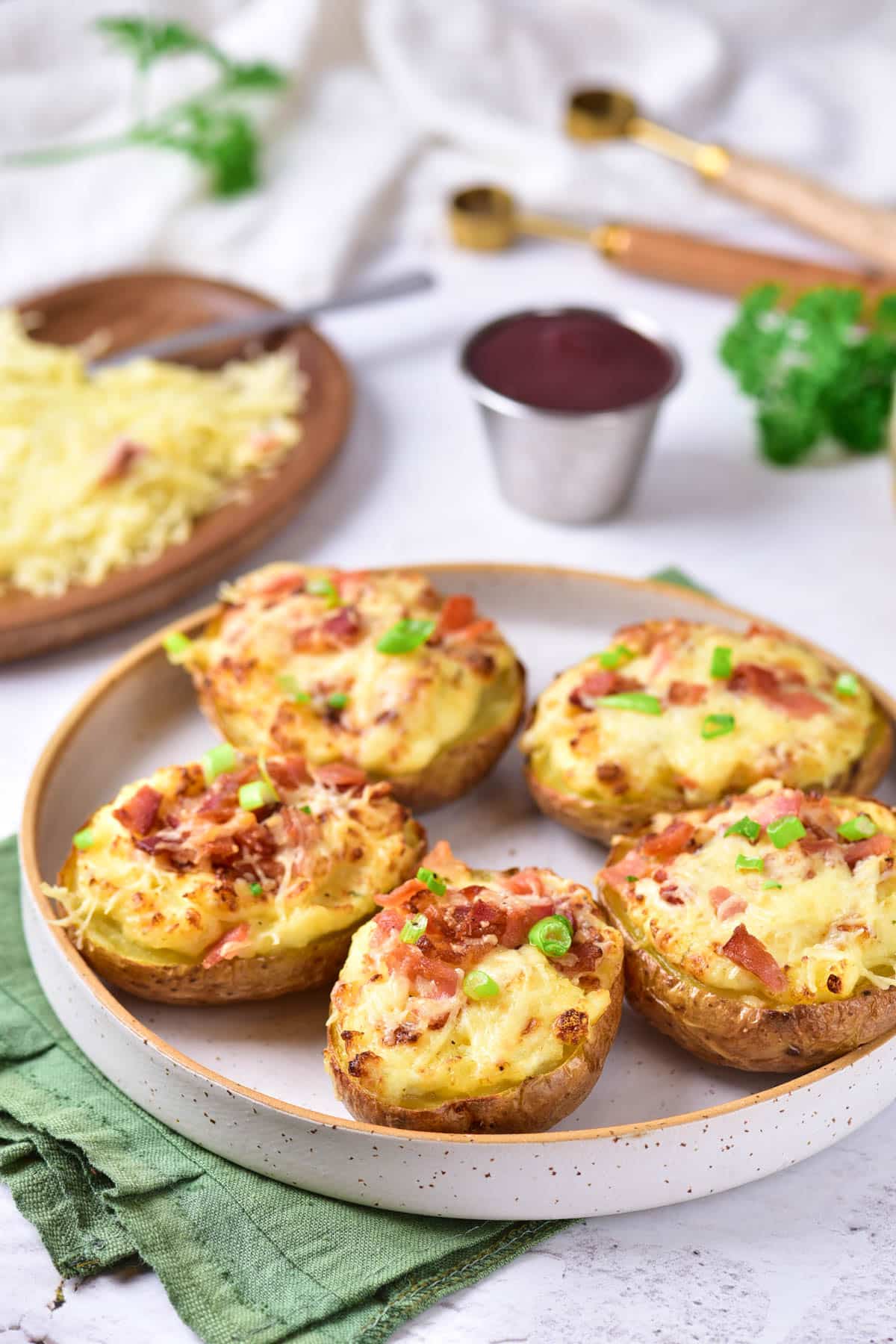 Baked potatoes with sour cream, cheese, green onions, and bacon on a plate.