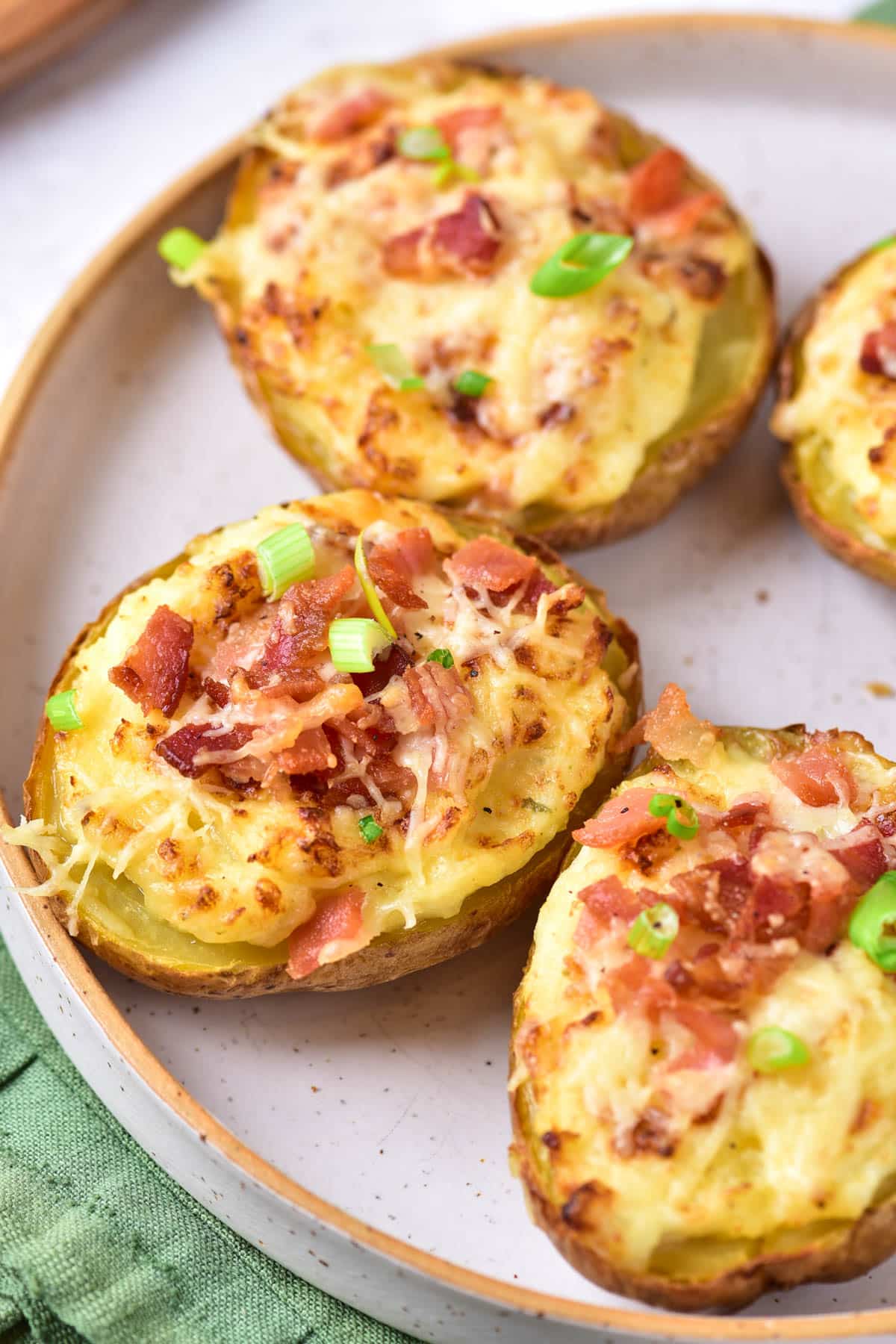 Baked potatoes with sour cream, cheese, green onions, and bacon on a plate.