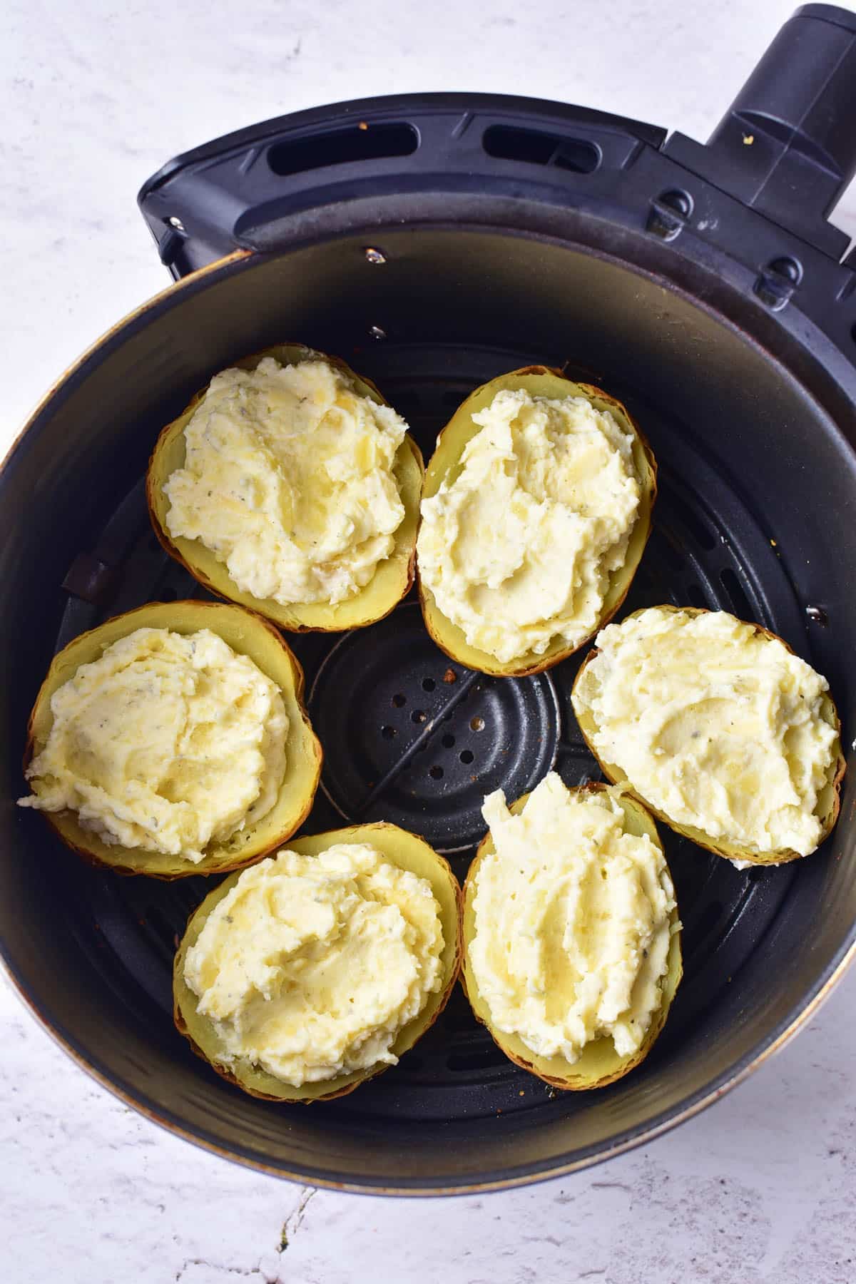 Stuffed potatoes in air-fryer basket.