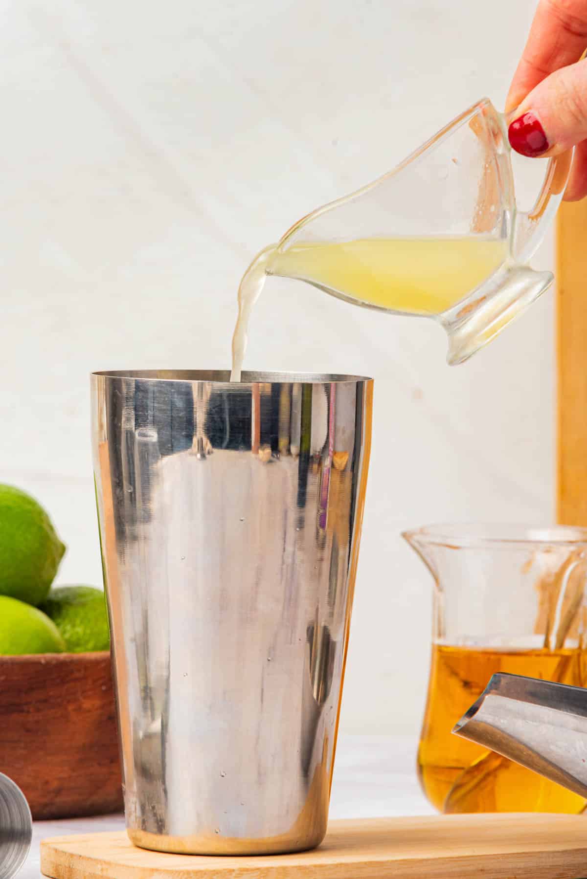 Adding lime juice to cocktail shaker.