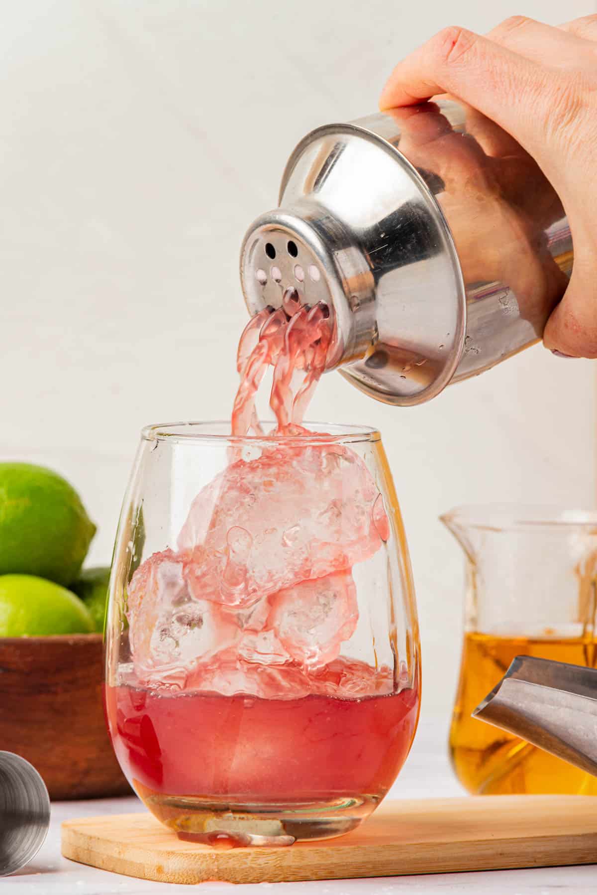 Pouring red drink into glass of ice.