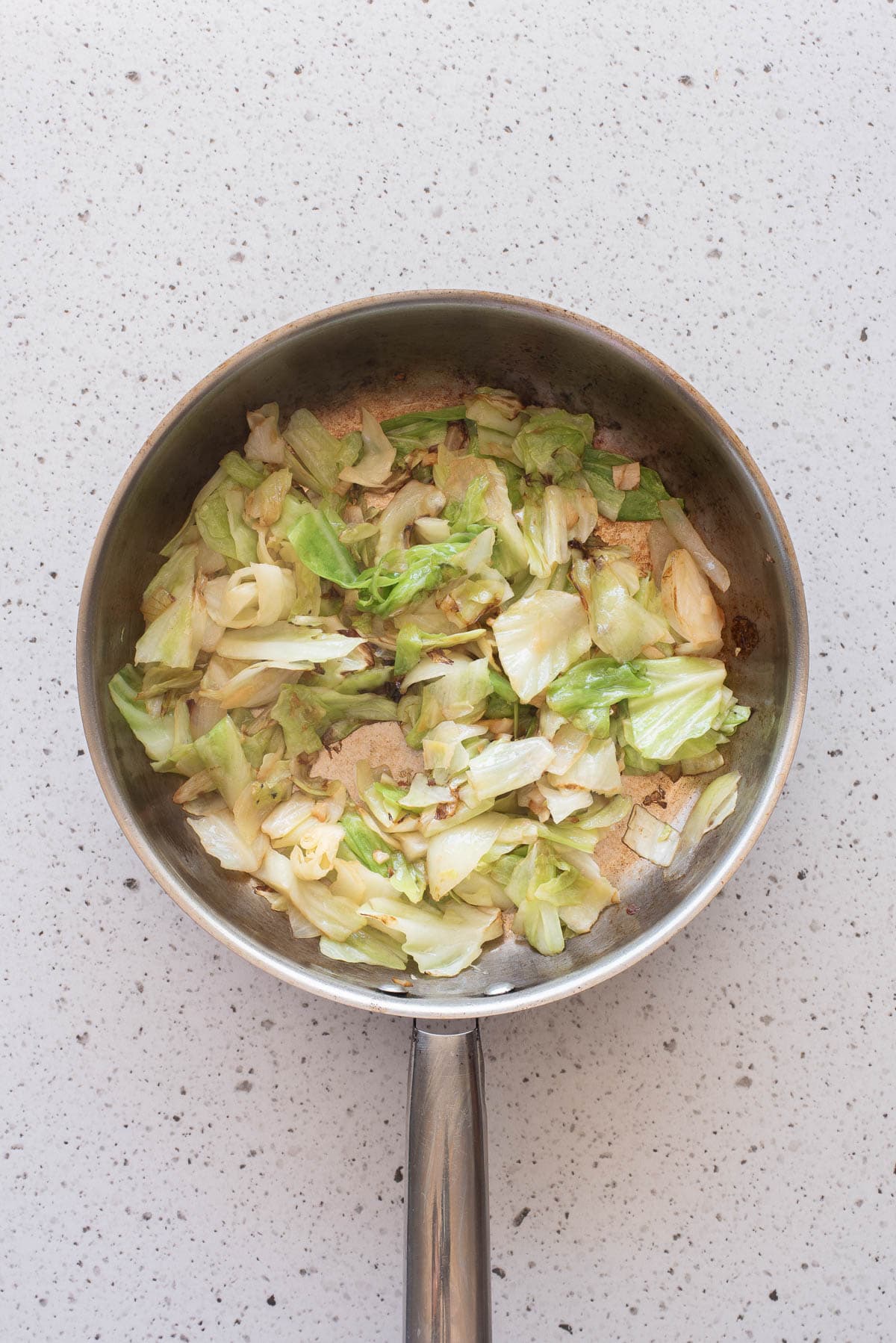 Cabbage and onions in a frying pan.