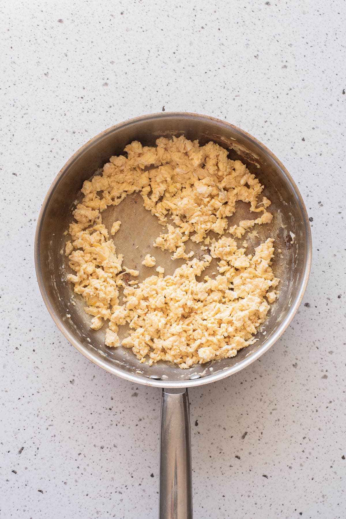 Scrambled eggs cooking in a frying pan.