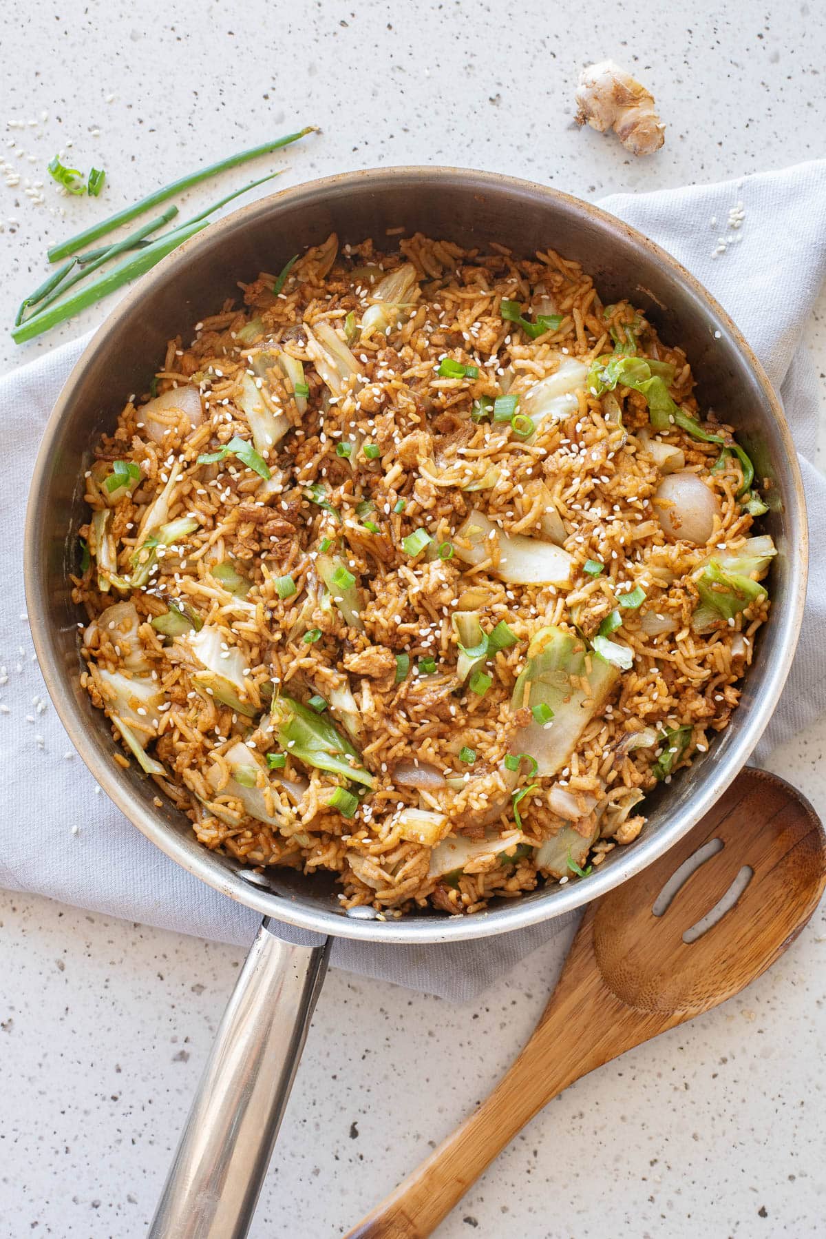 Egg fried rice in frying pan with wooden serving spoon on side.