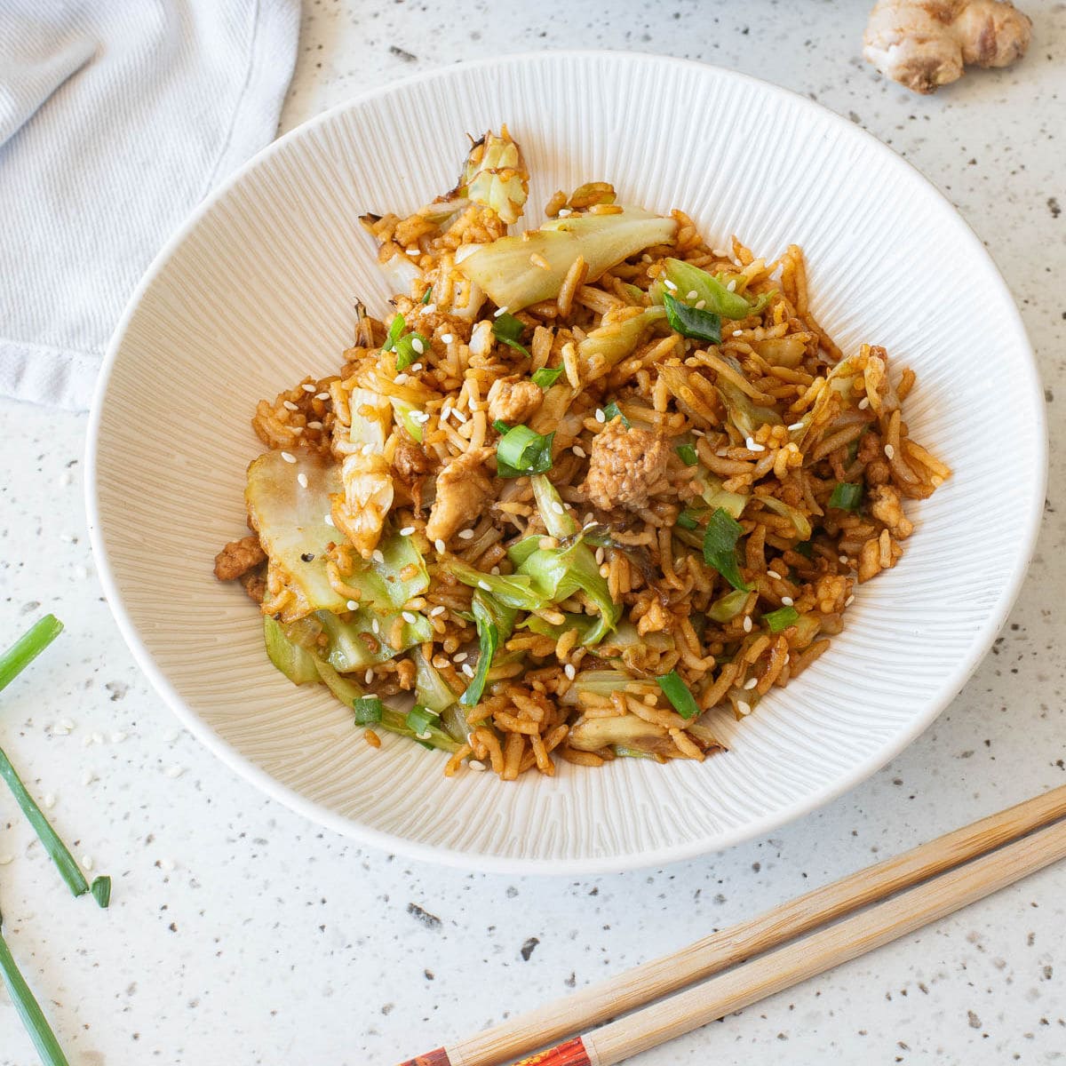 Egg fried rice in a white bowl with chopsticks in front.