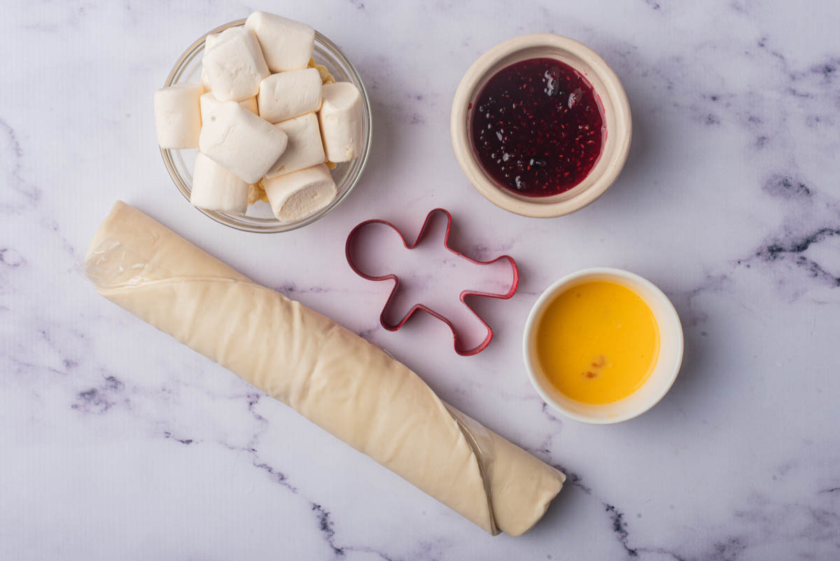 Roll of dough, marshmallows, raspberry jam, egg yolk, with cookie cutter in center.